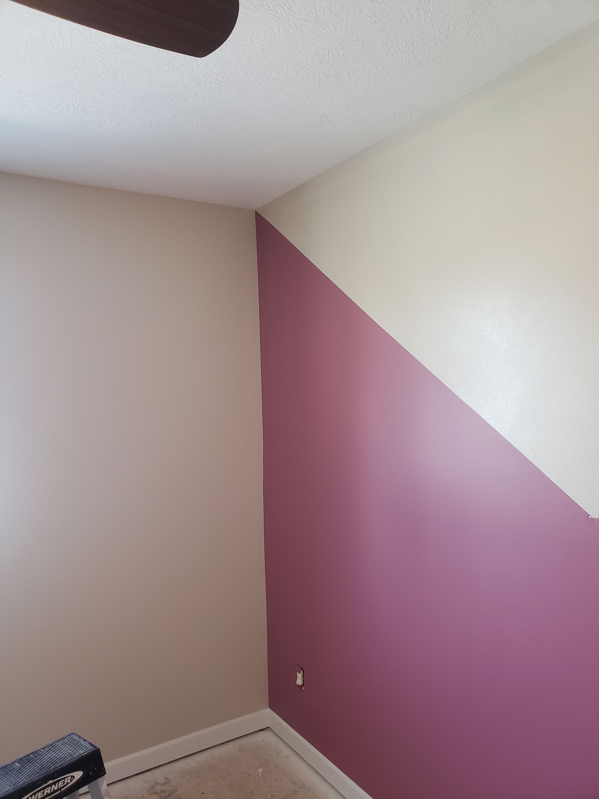 A room with pink and white walls and a ceiling fan.