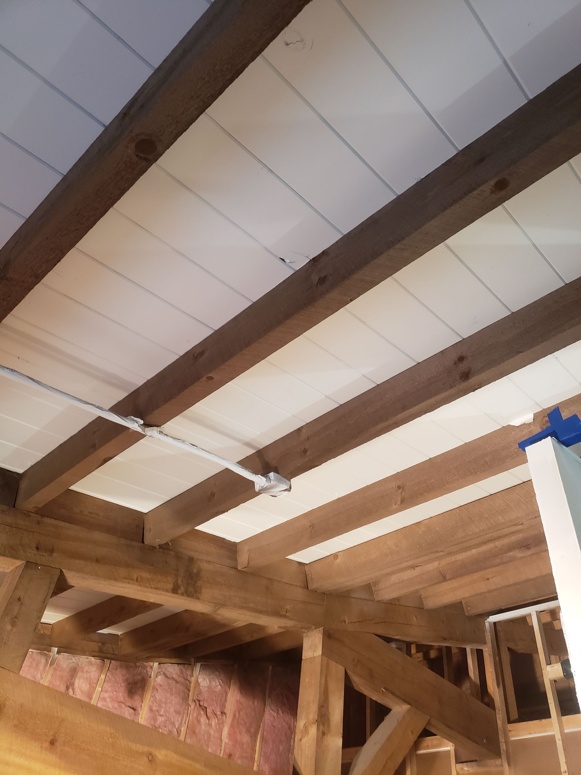 A ceiling with wooden beams and a white ceiling