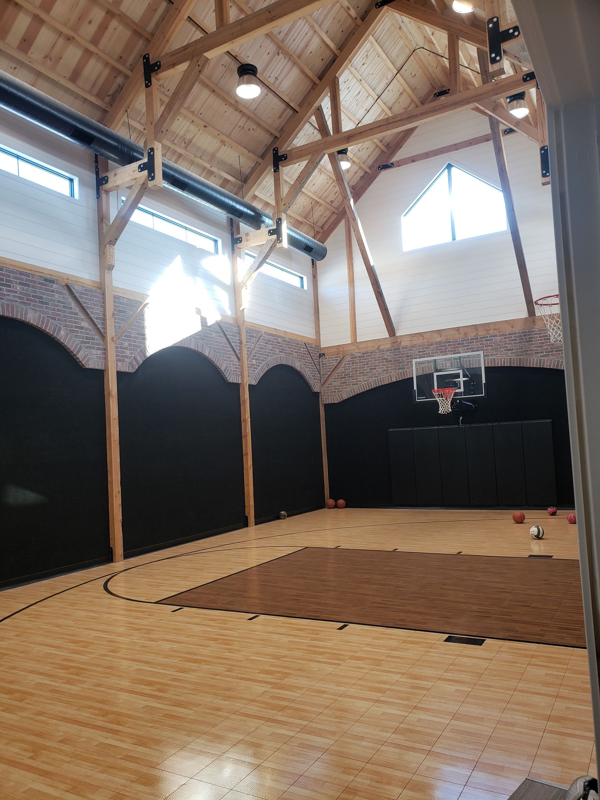 A large indoor basketball court with a wooden floor and a basketball hoop.
