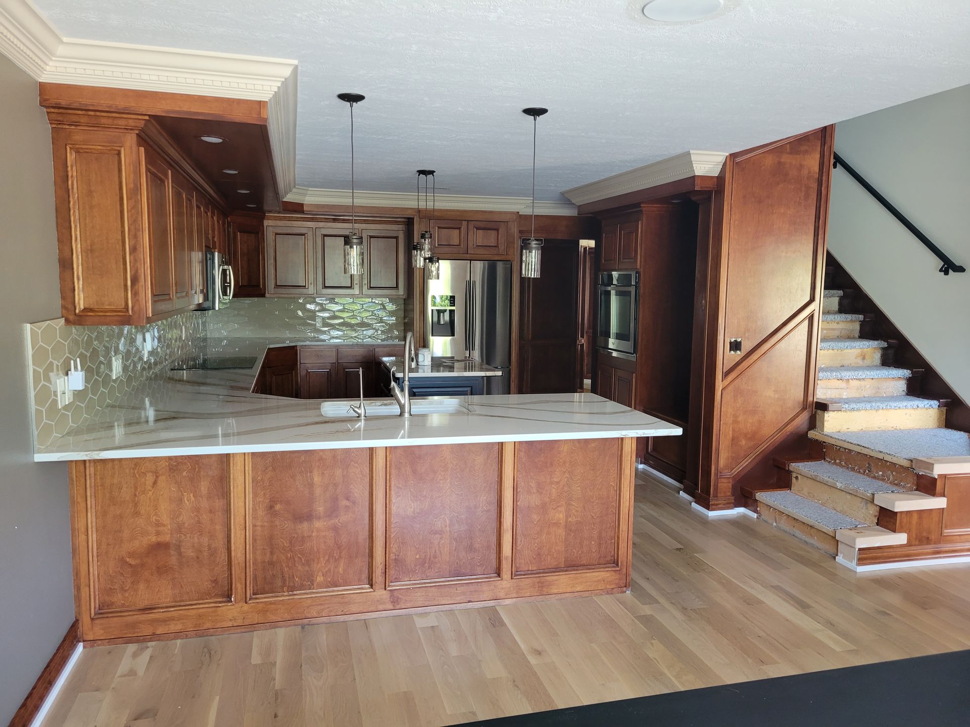 A kitchen with wooden cabinets and marble counter tops