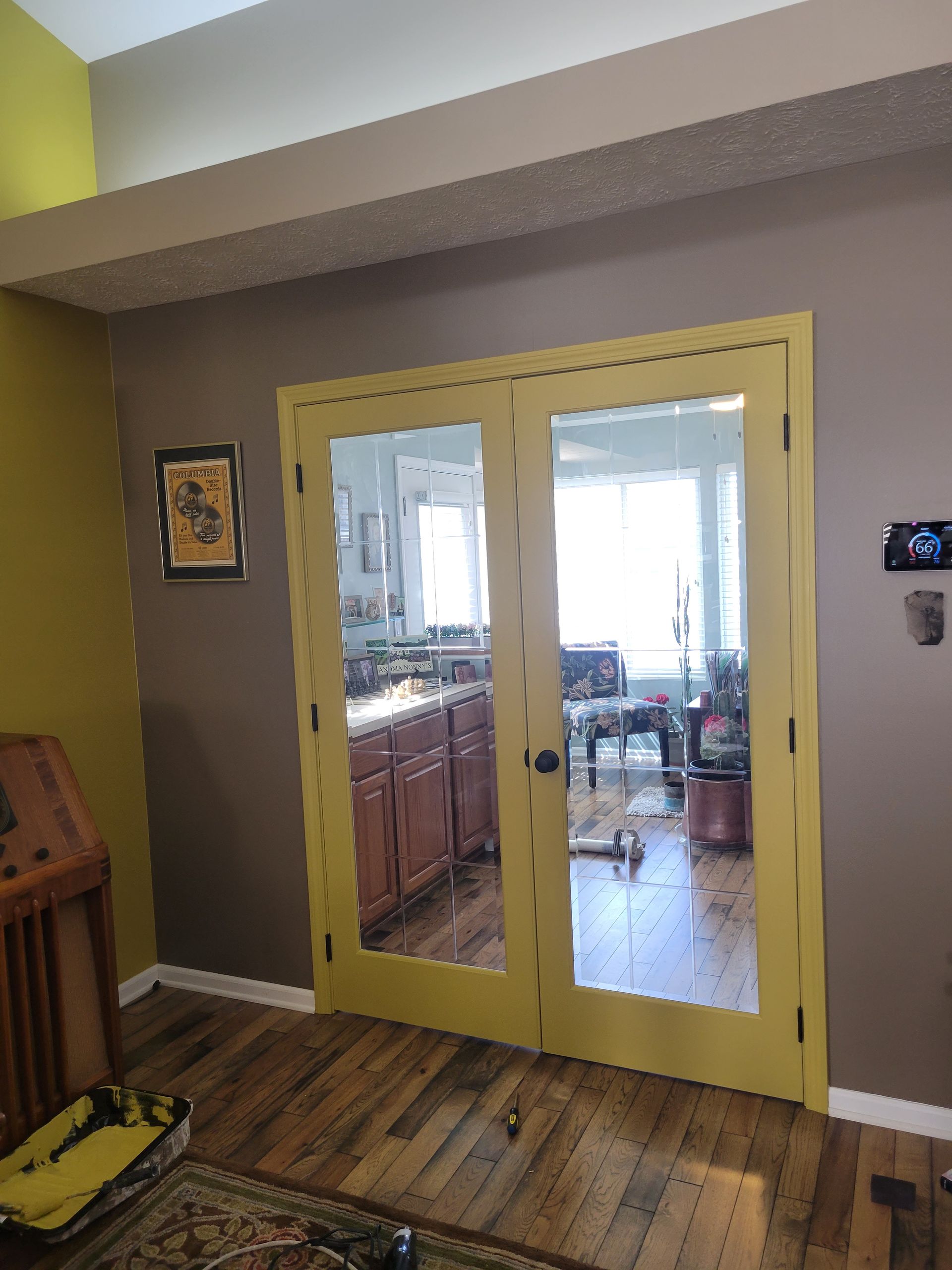 A living room with a yellow door and a mirror