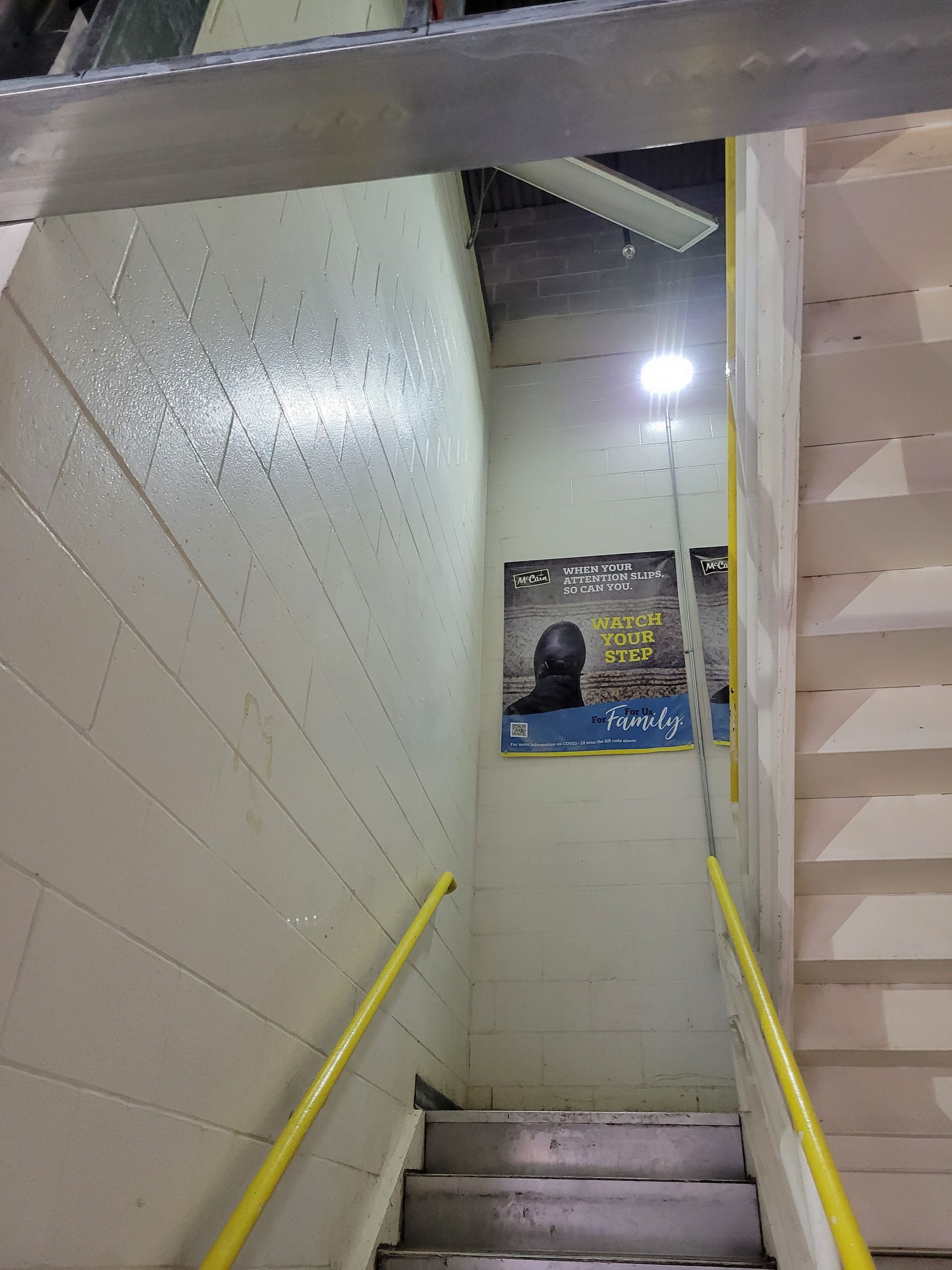 A staircase with a yellow railing and a sign on the wall.