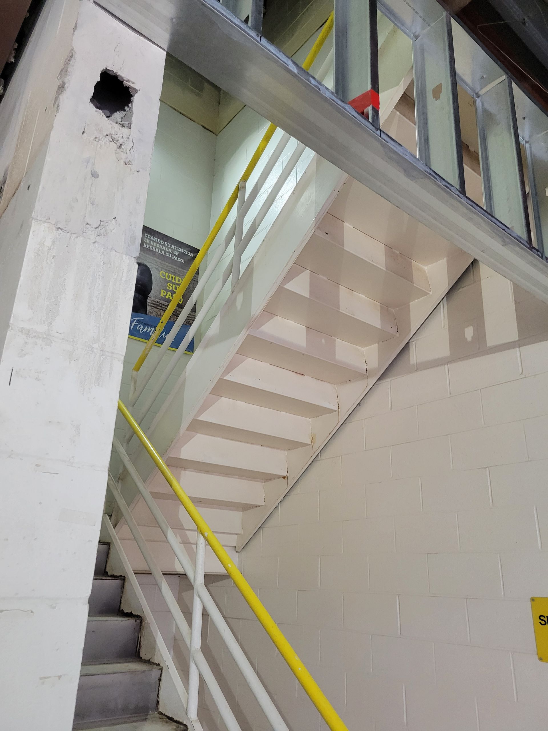 A staircase with a yellow railing and a yellow sign that says emergency