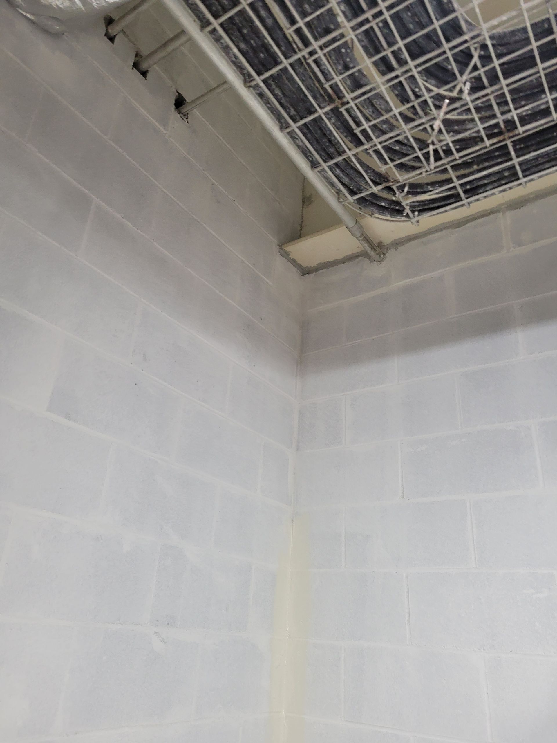 A room with a brick wall and a ceiling with wires hanging from it.