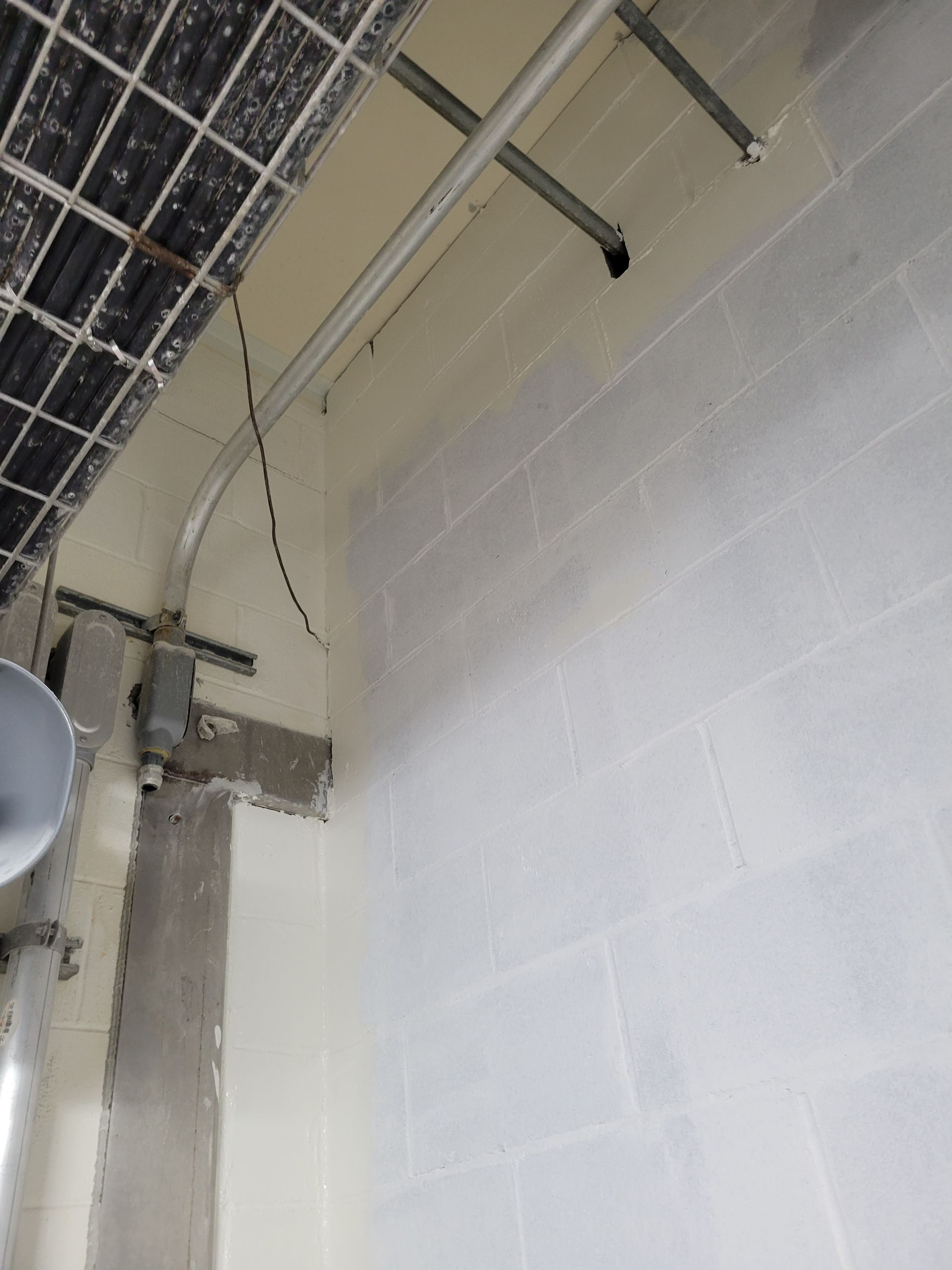 A white brick wall with a metal pipe hanging from it