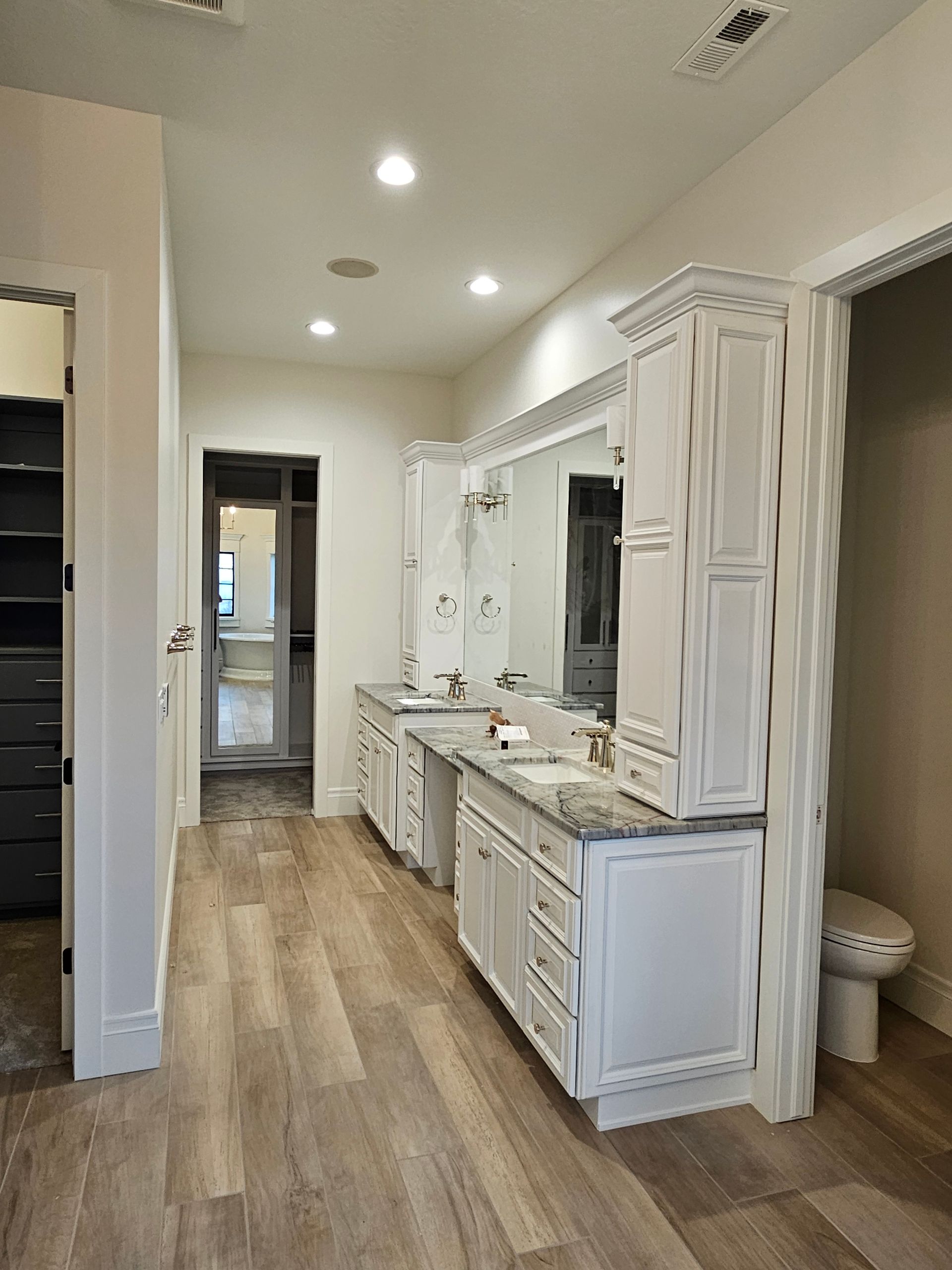 A bathroom with two sinks , a toilet and a walk in closet.