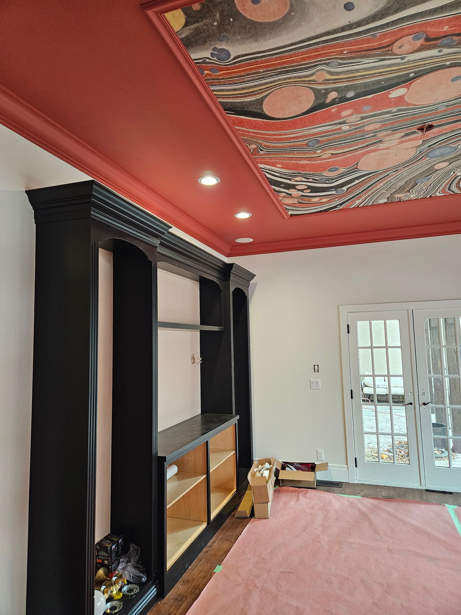 A living room with a red ceiling and black shelves