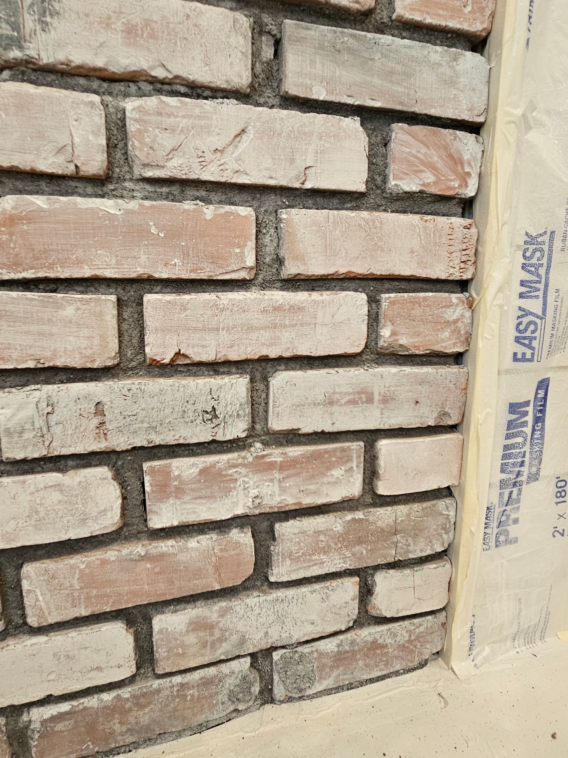 A close up of a brick wall with easy mask on it