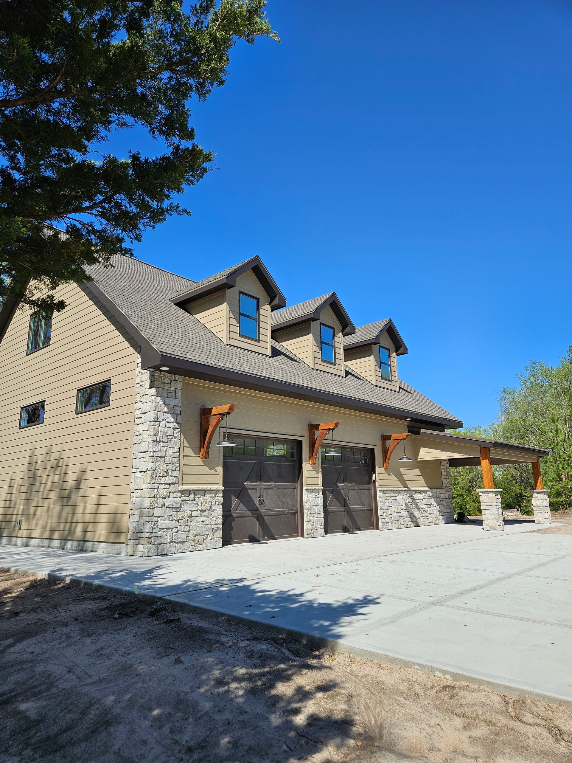 A large house with two garage doors and a tree in front of it.