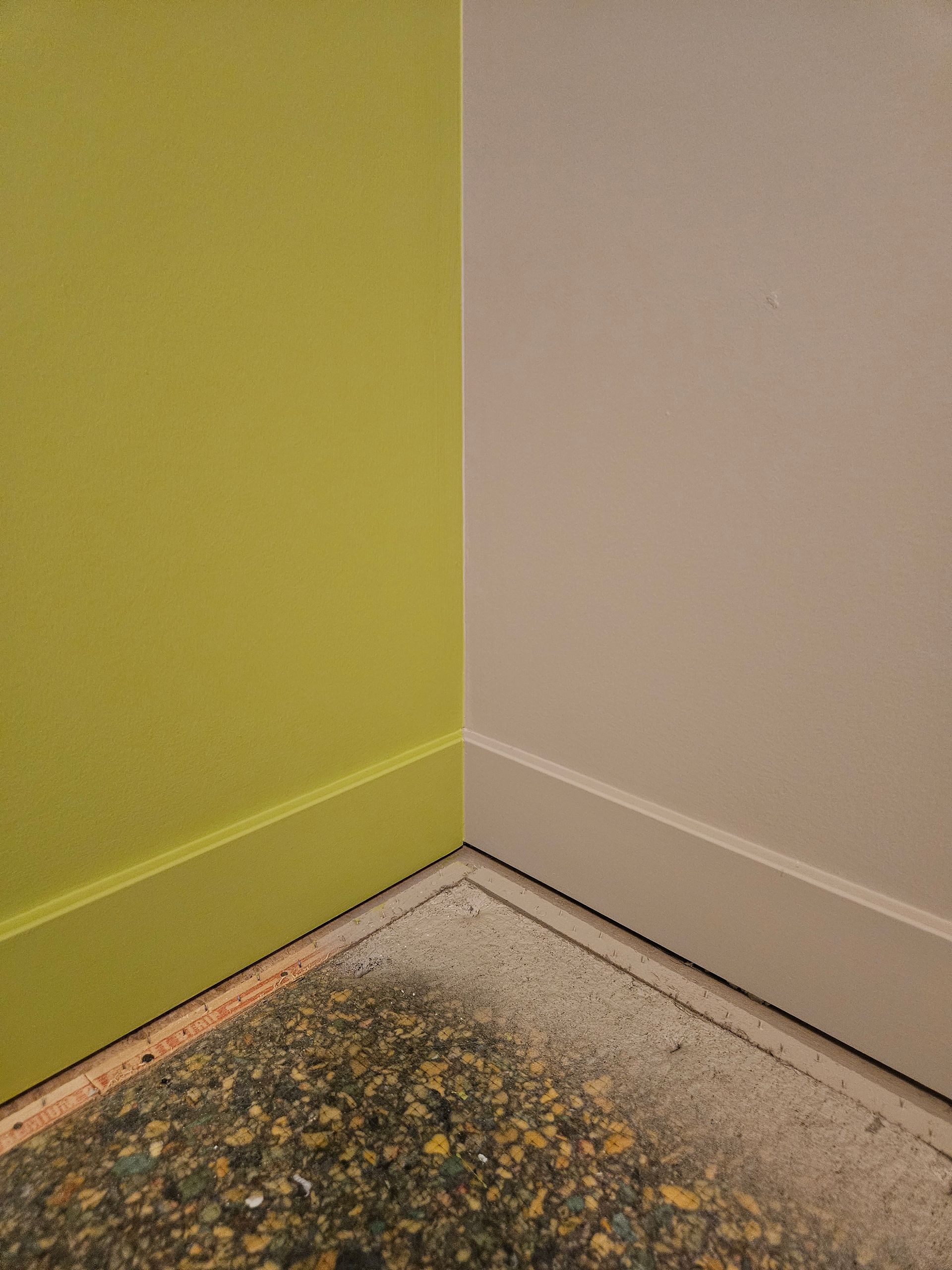 A corner of a room with a yellow wall and a white wall.