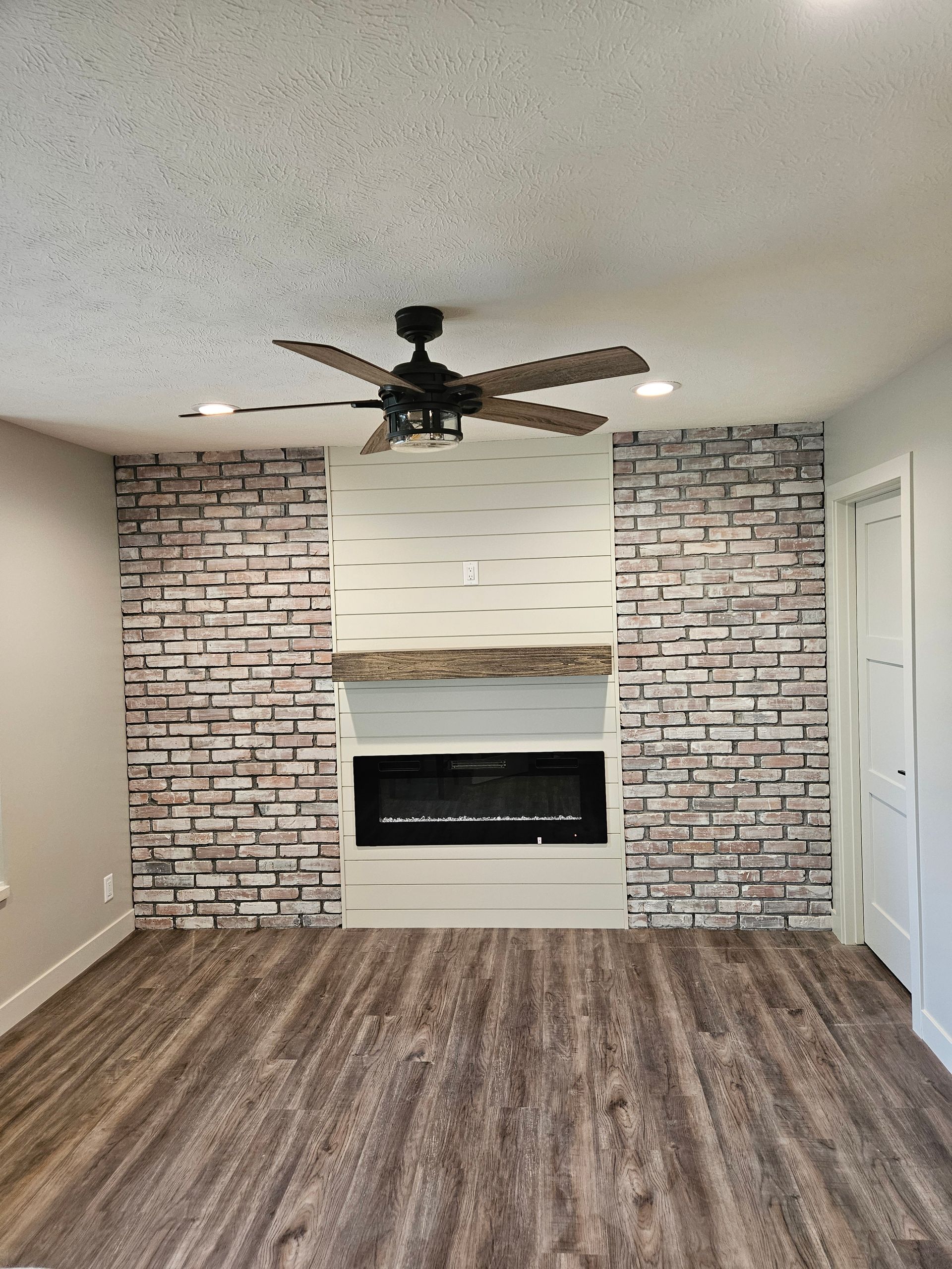 A living room with a fireplace and a ceiling fan.