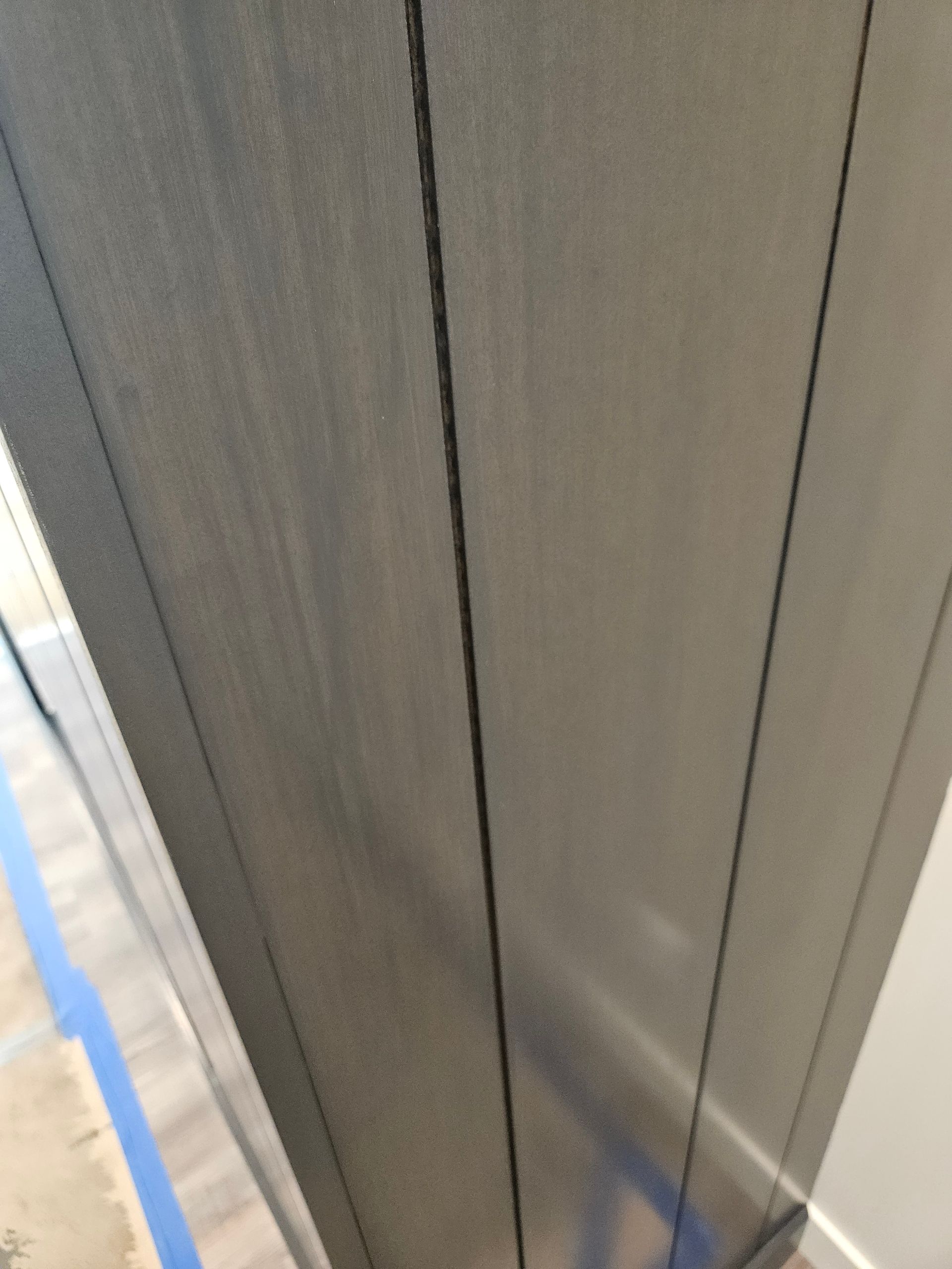 A close up of a gray wall with blue tape on it