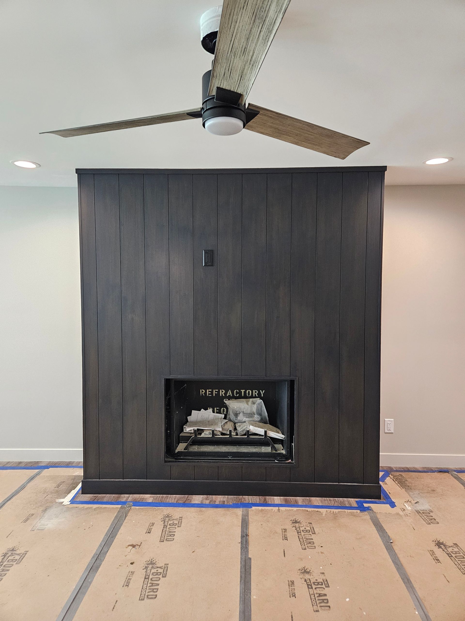 A living room with a fireplace and a ceiling fan