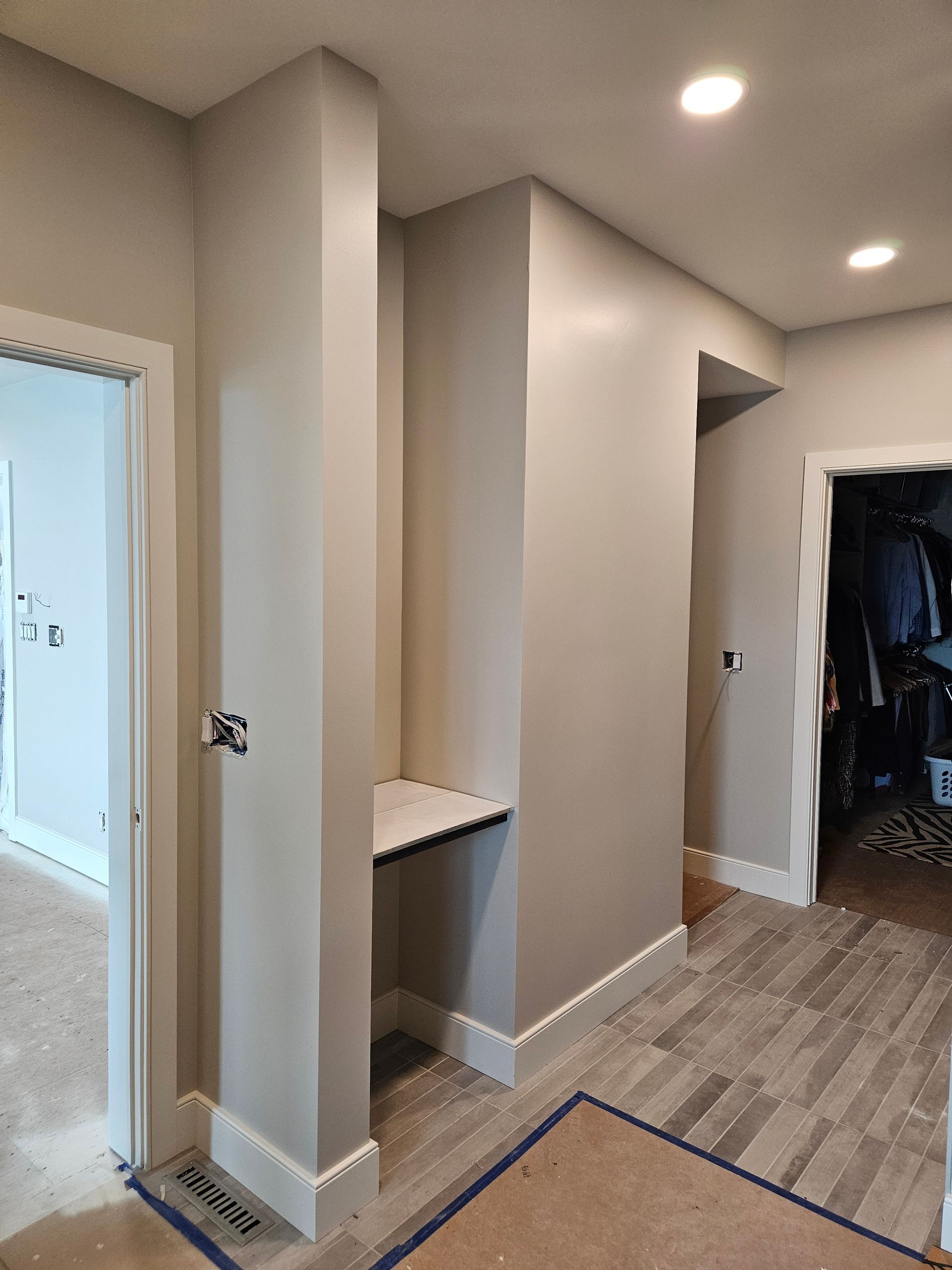 A hallway with a wooden floor and a shelf on the wall.
