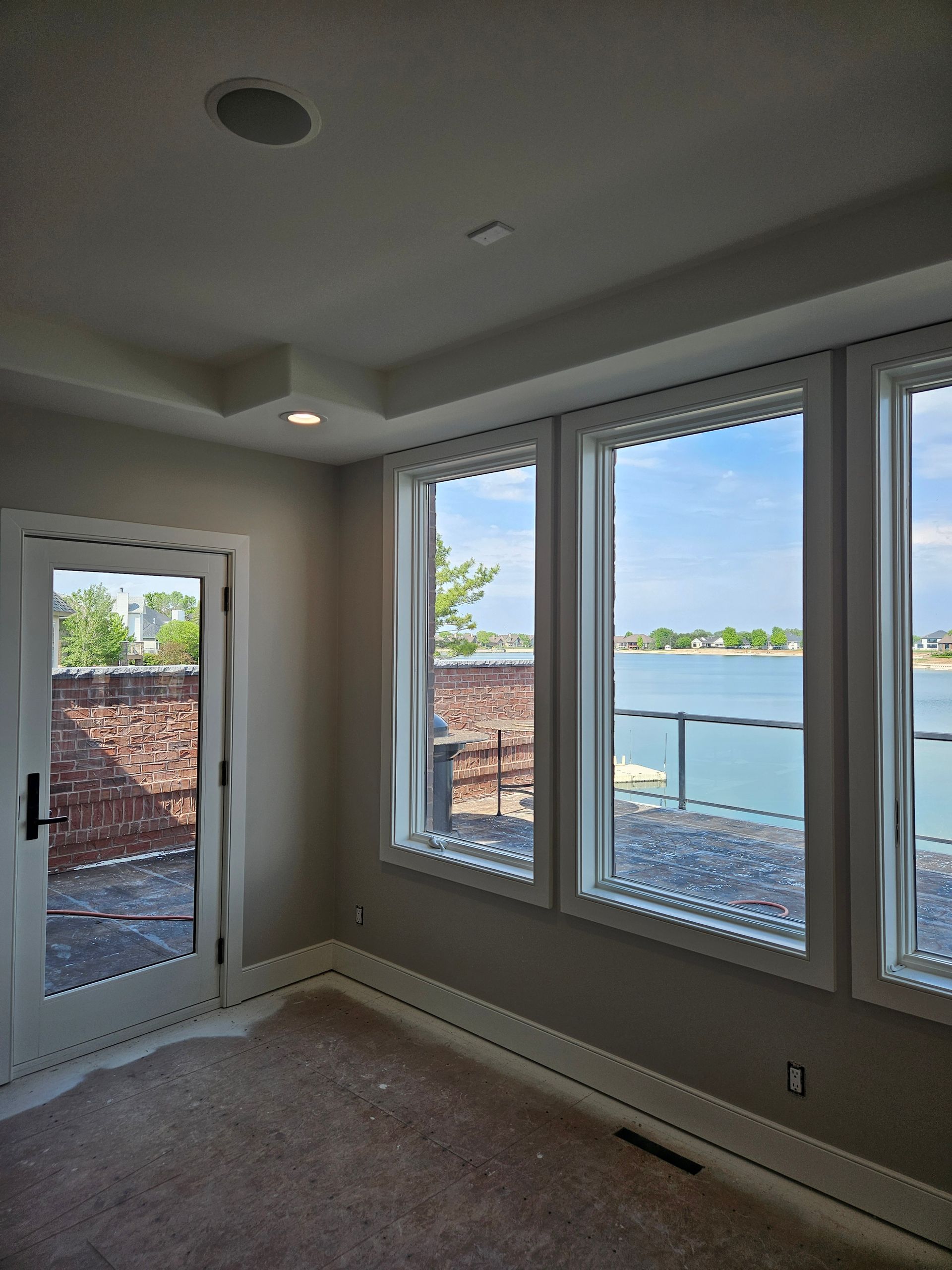 A room with a lot of windows and a view of a lake.