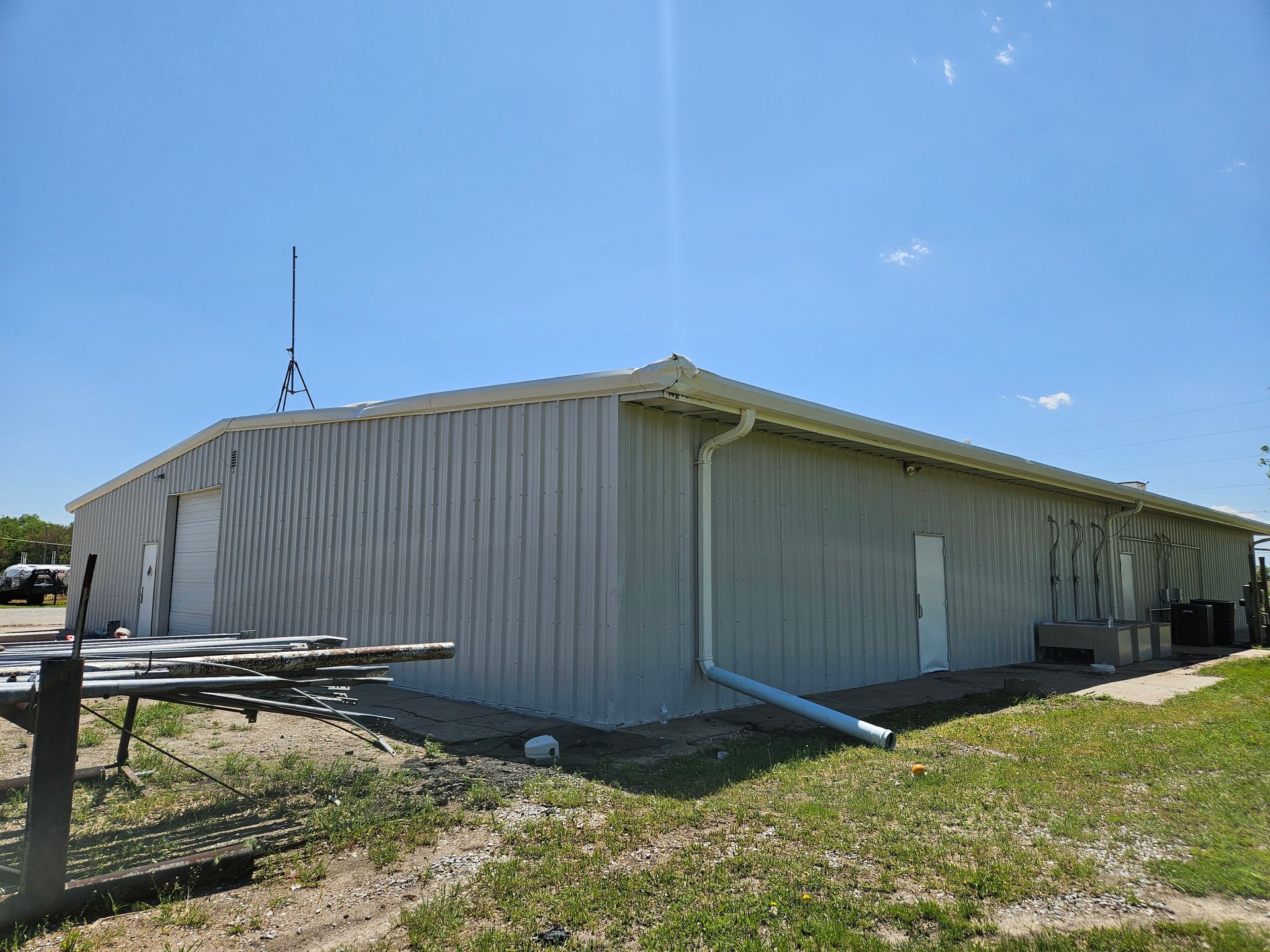 A large metal building is sitting in the middle of a grassy field.