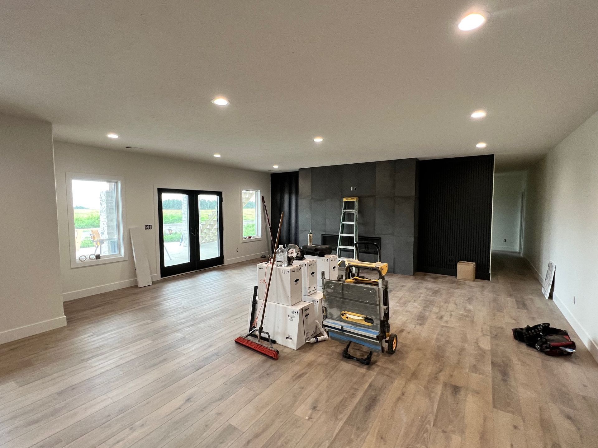 A large empty room with hardwood floors and a ladder.