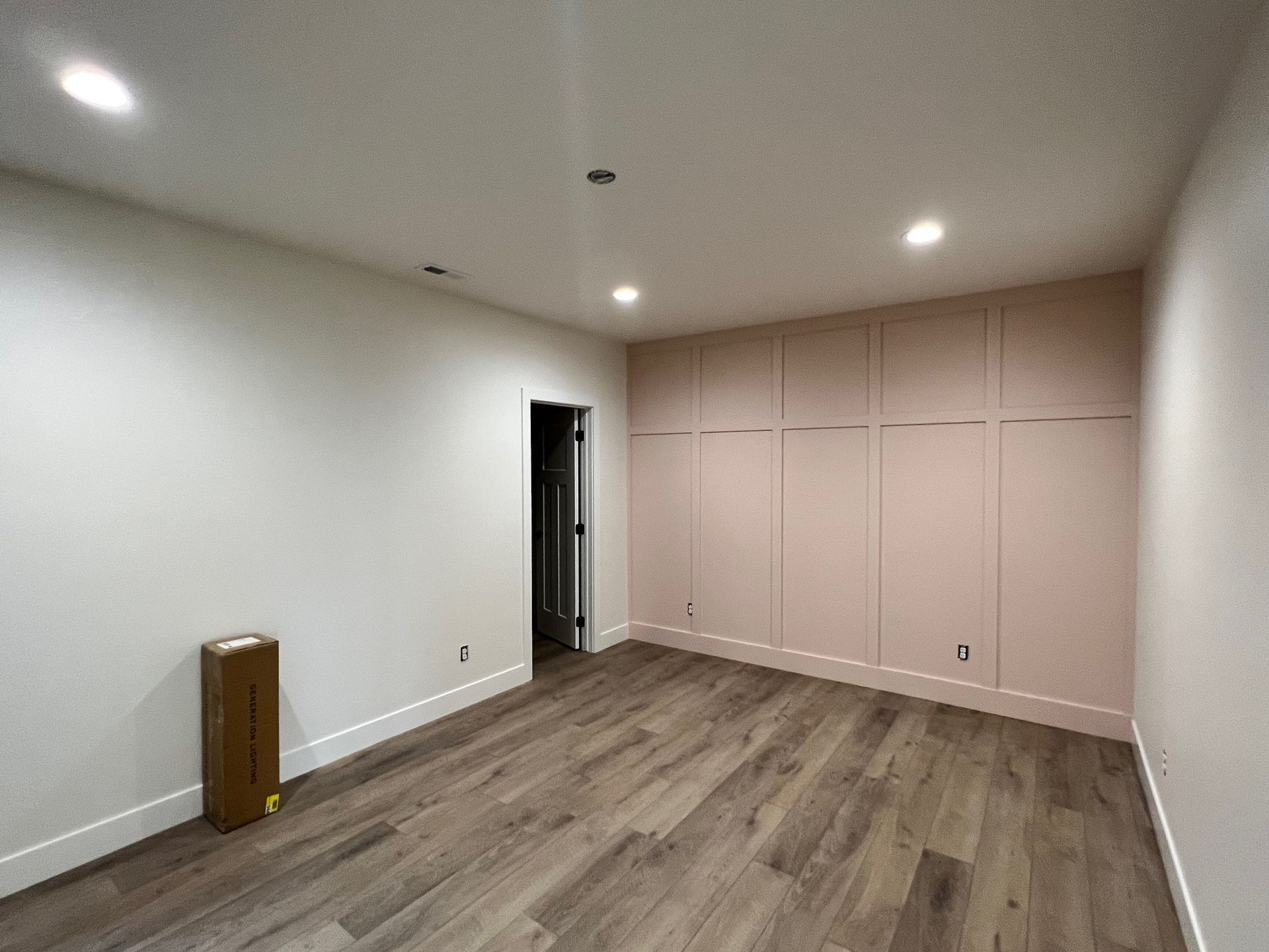 An empty room with hardwood floors and white walls.