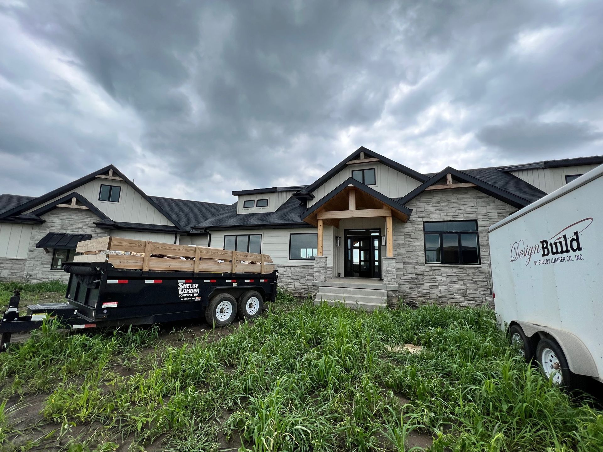 A large house under construction with a trailer parked in front of it.
