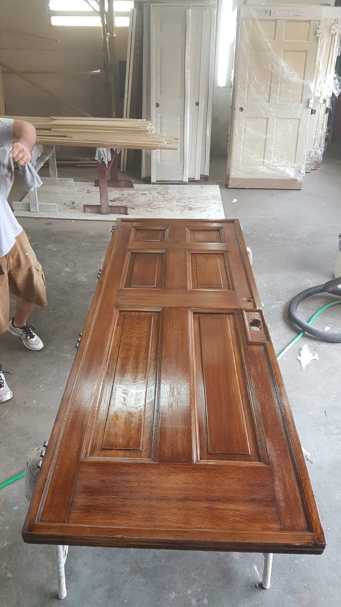 A man is standing next to a wooden door in a room.