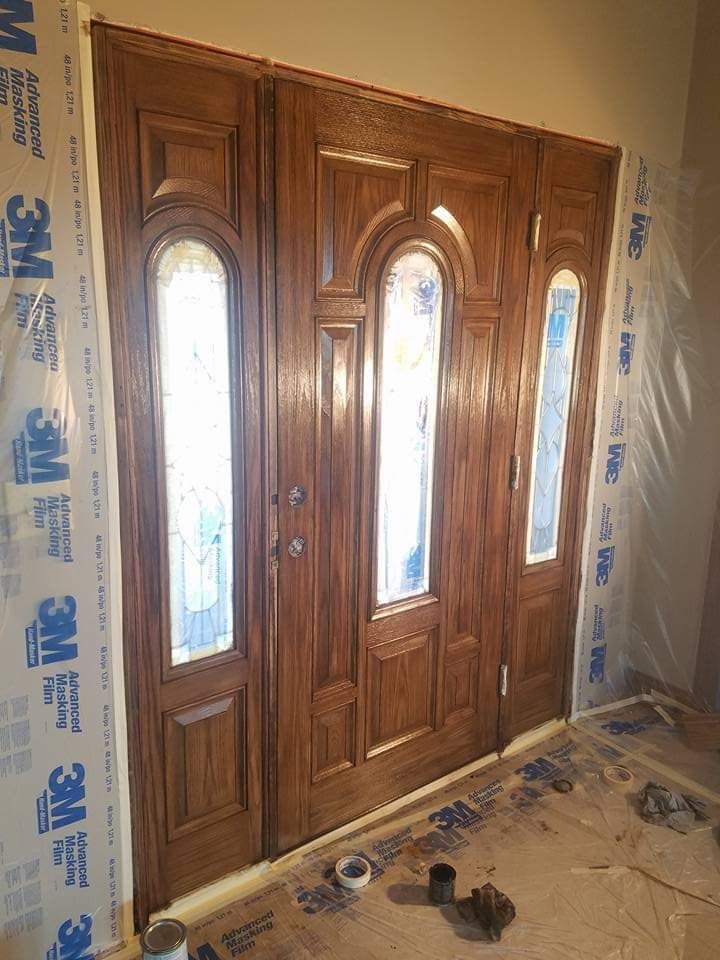 A large wooden door is being painted in a room.