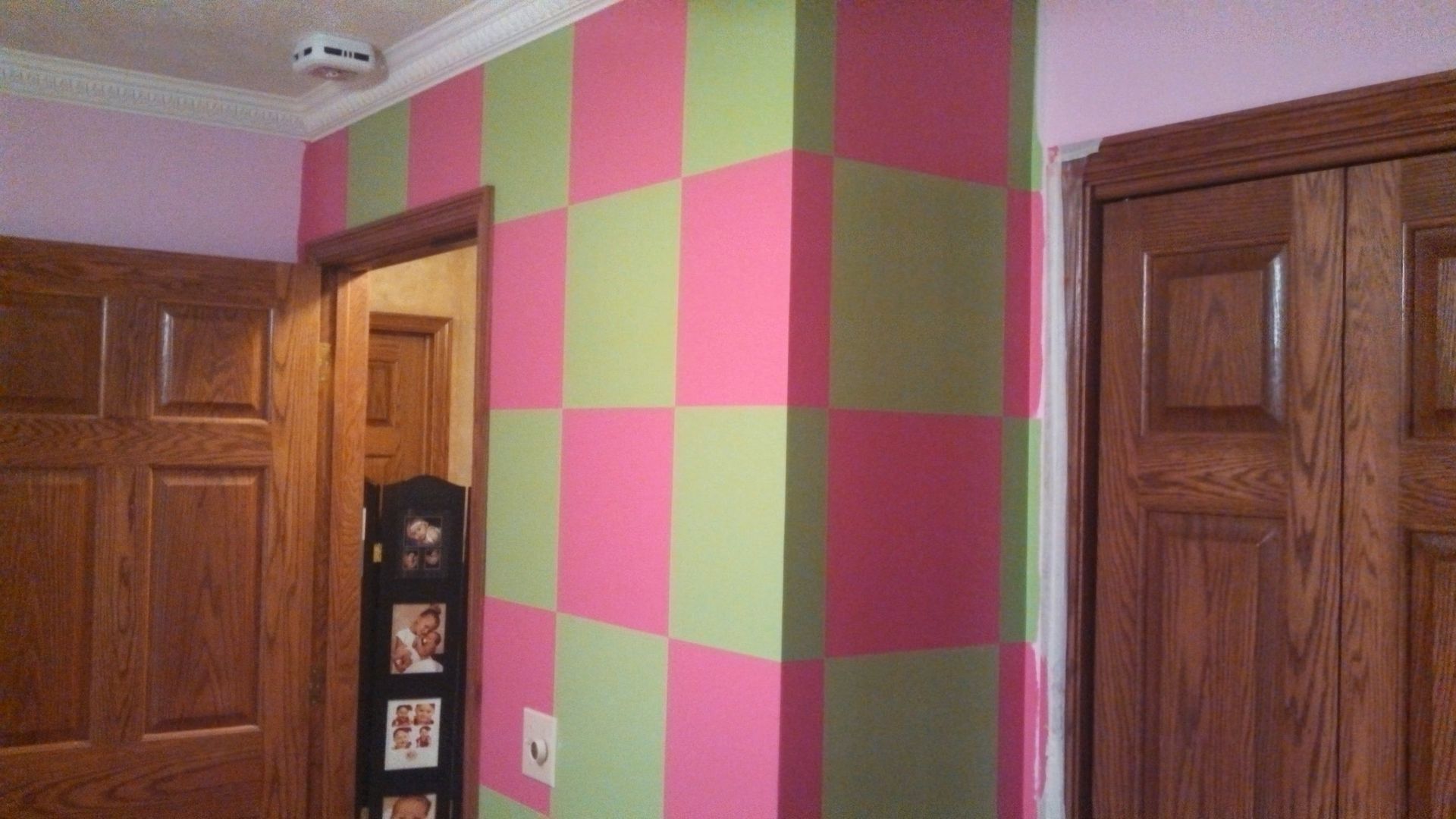 A room with pink and green checkered walls and wooden doors.