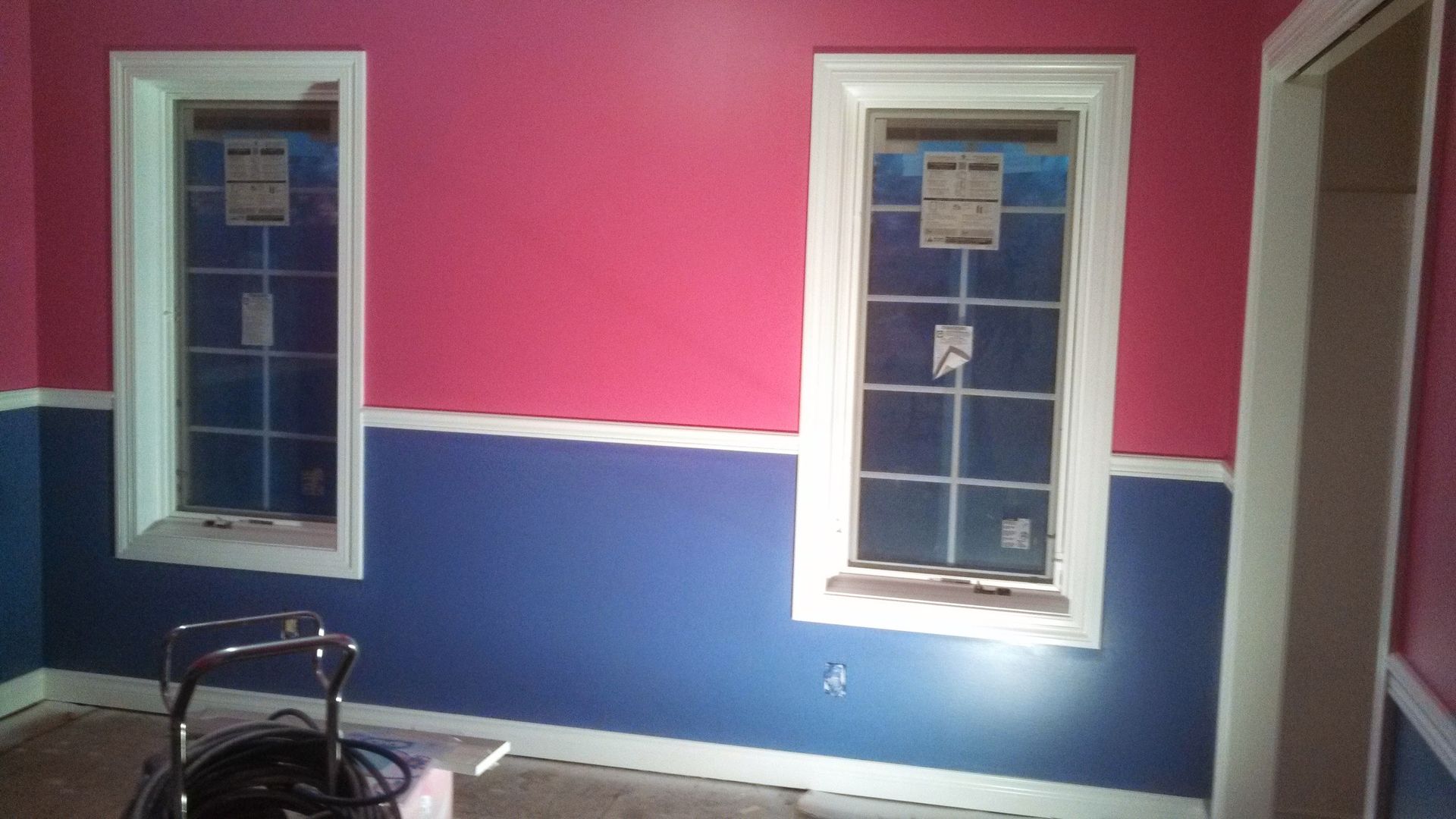A room with pink and blue walls and two windows