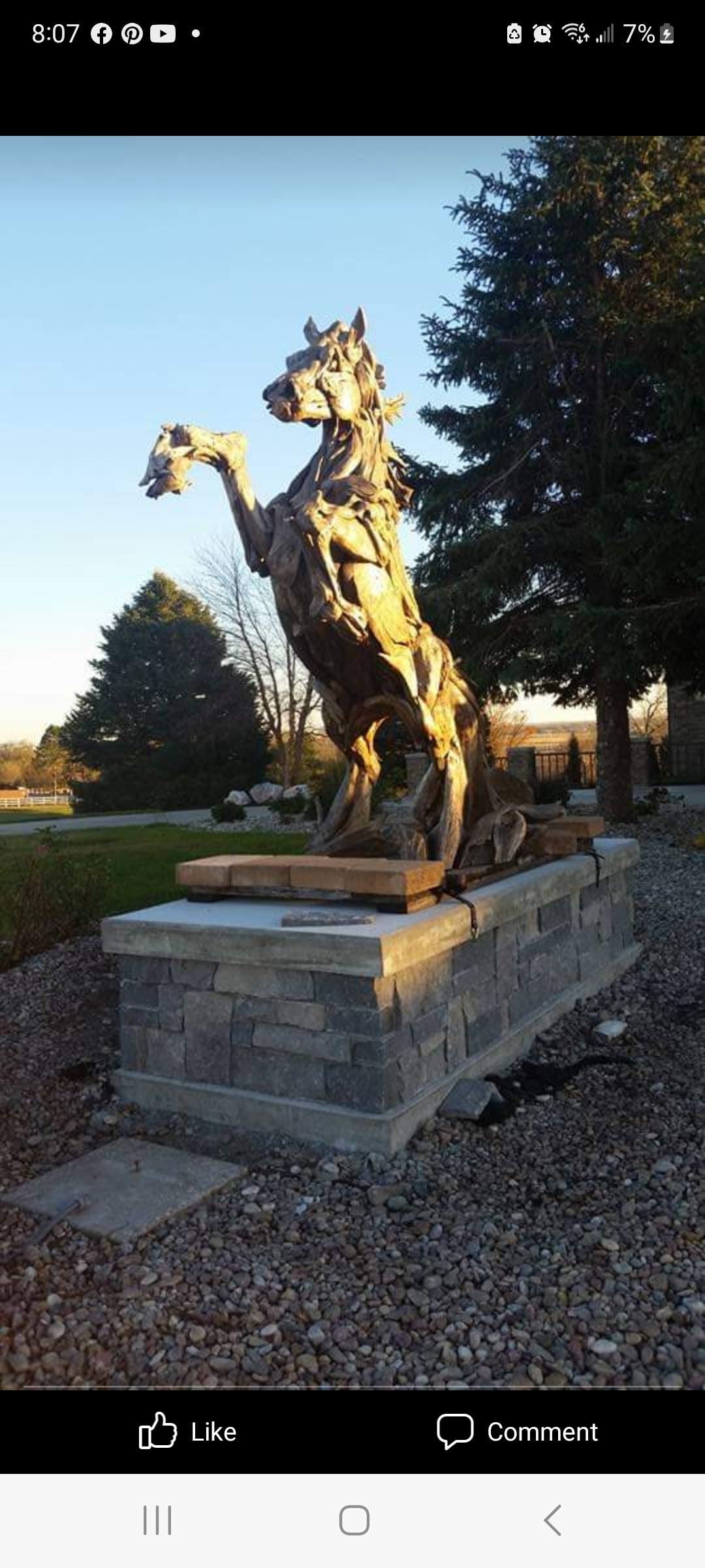 A statue of a horse standing on its hind legs in a park.