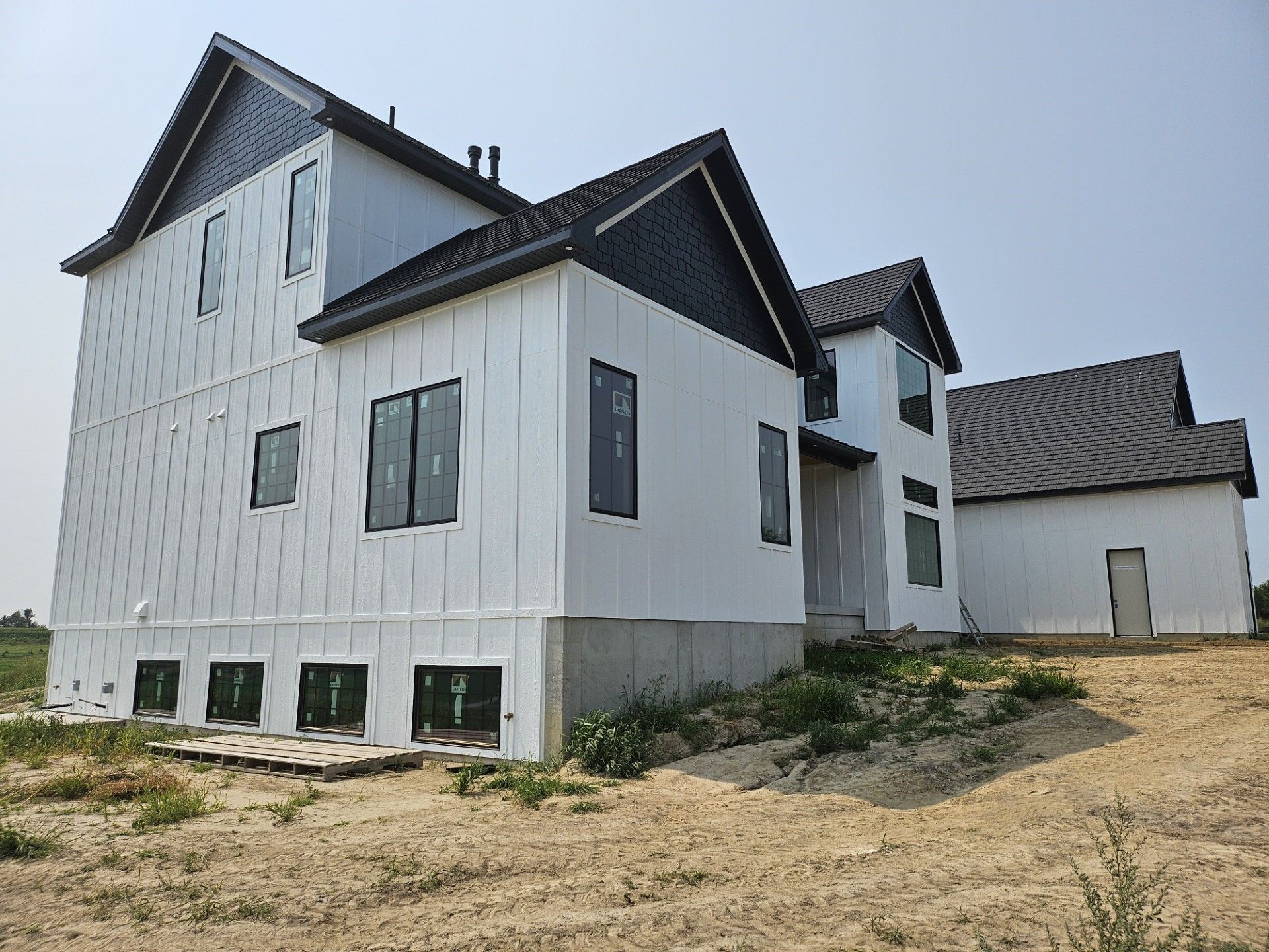 A large white house is sitting on top of a dirt field.