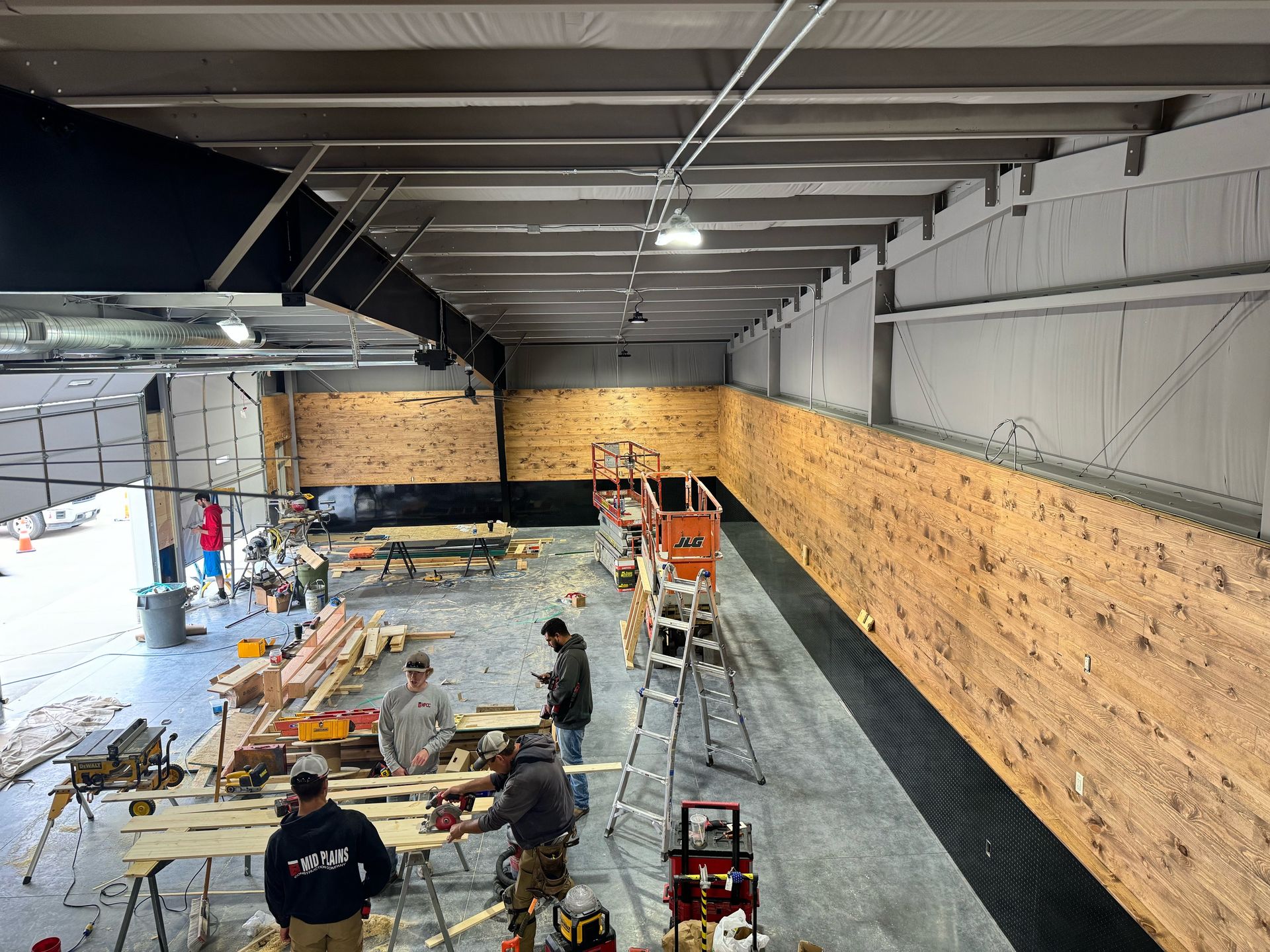 A group of people are working on a wooden wall in a building.