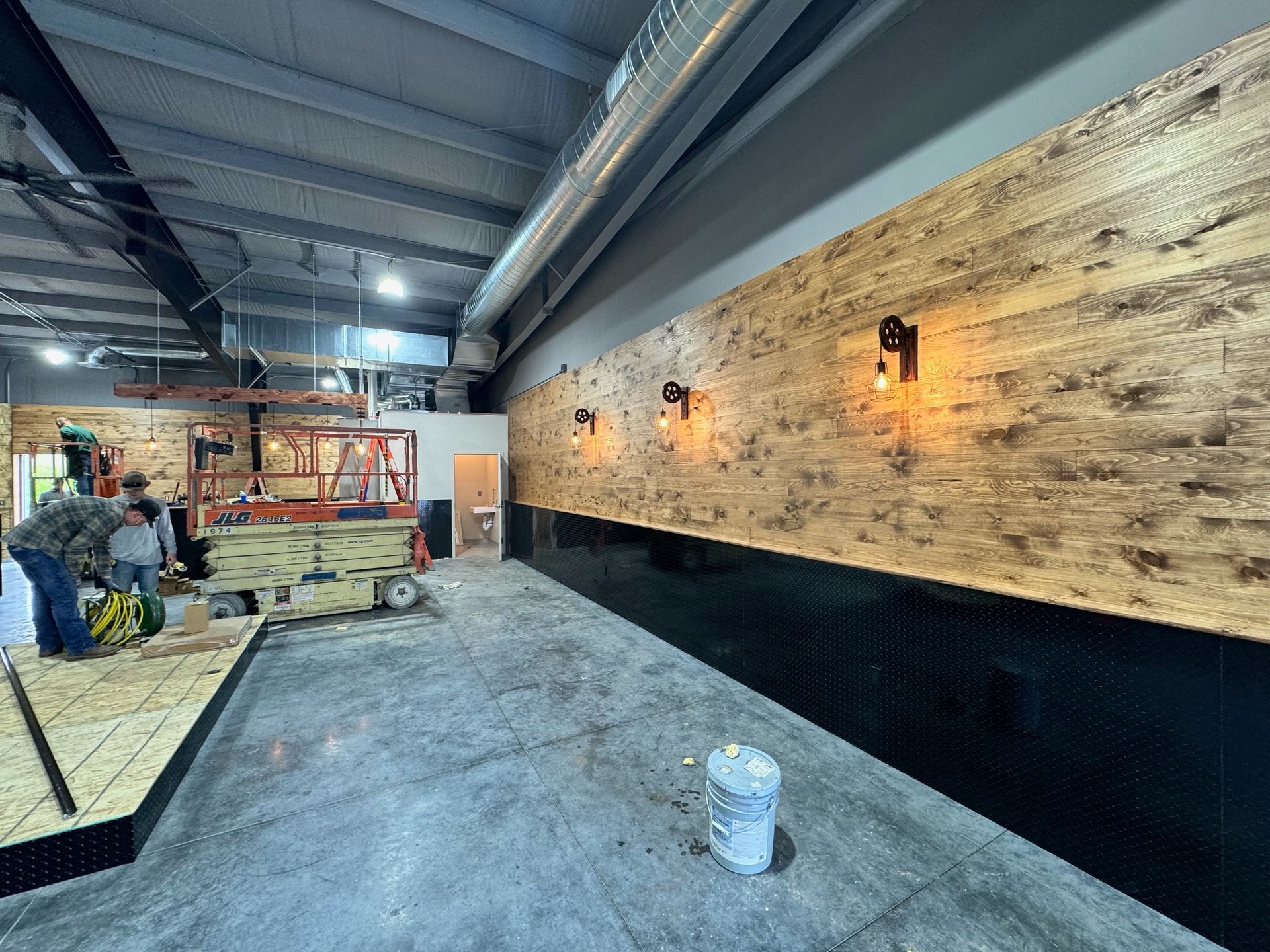 A large room with wooden walls and a bucket on the floor.