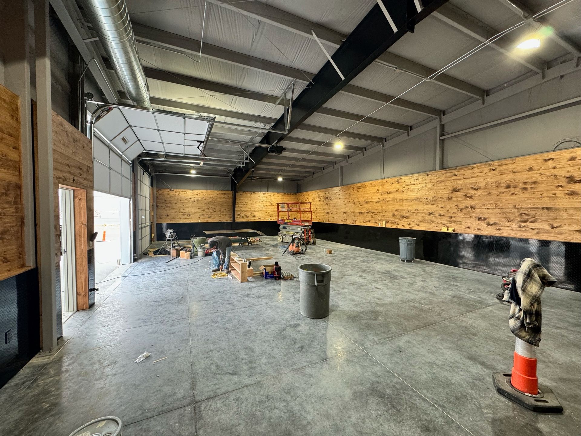 A large empty warehouse with a wooden wall and a concrete floor.