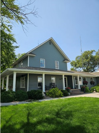 A blue house with a white porch and a blue sky in the background