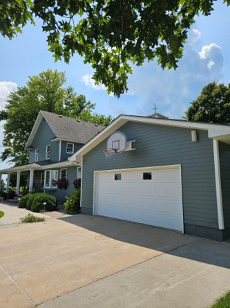 A house with a white garage door and a basketball hoop on the side of it.