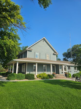A large house with a porch and a blue sky in the background