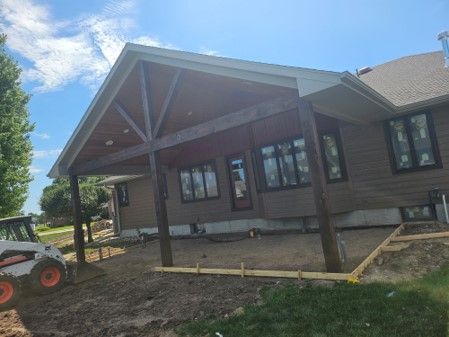 A bobcat is parked in front of a house under construction.