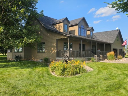 A large house with a large porch and a large lawn in front of it.