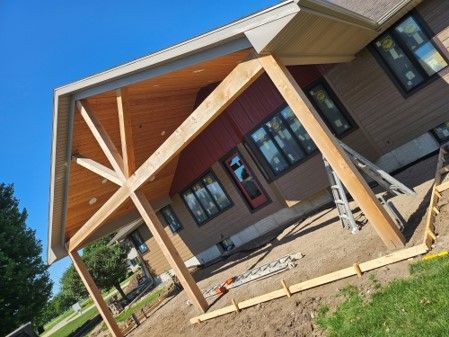 A house with a covered porch and a ladder in front of it.