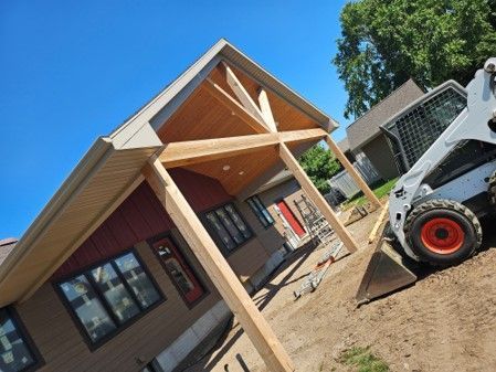A bobcat is parked in front of a house under construction.