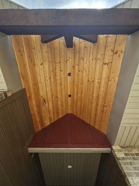 A wooden ceiling with a red roof and a ceiling fan.