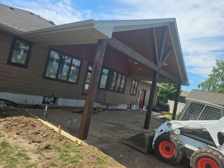 A bobcat is parked in front of a house under construction.