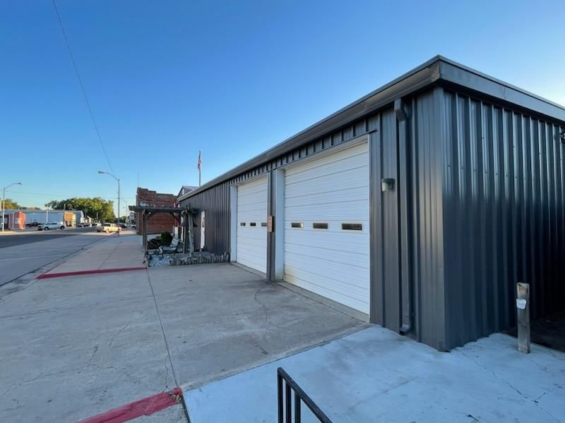 A large gray metal building with two white garage doors on the side