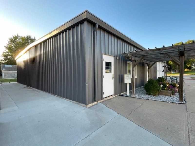 A gray metal building with a white door and a pergola