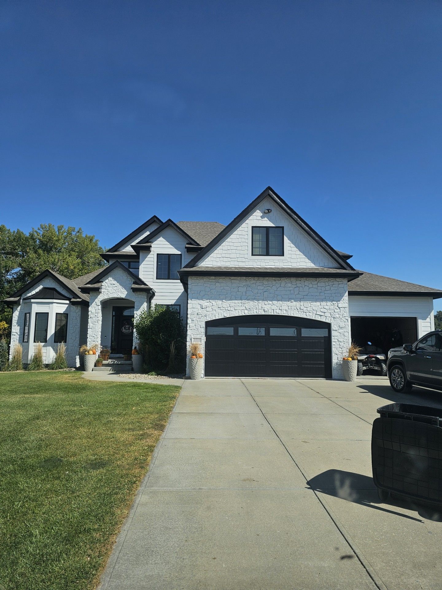 A large white house with a black garage door and a black truck parked in front of it