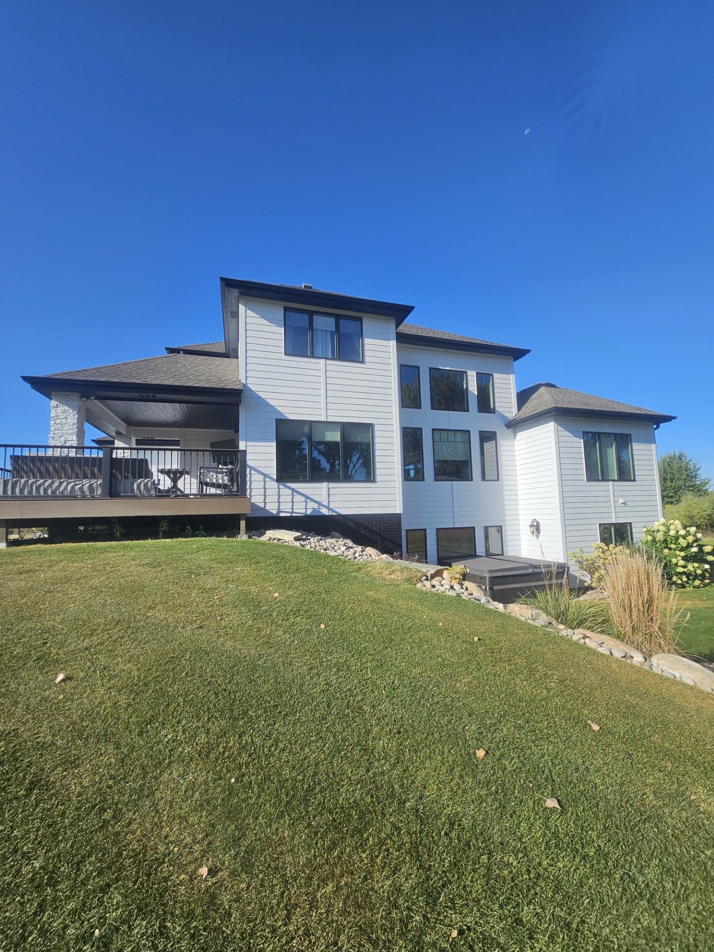 A large white house is sitting on top of a grassy hill