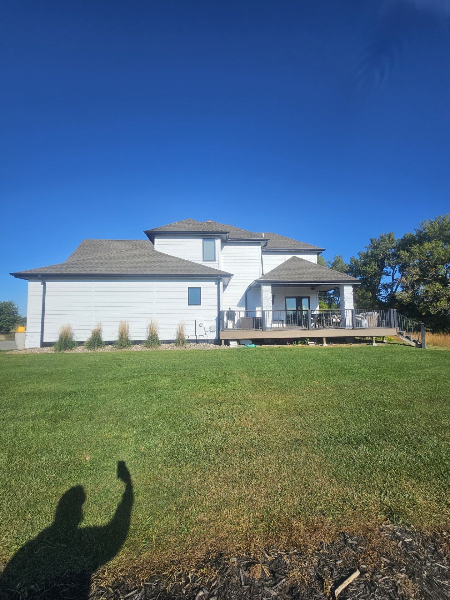 A large white house is sitting on top of a lush green field