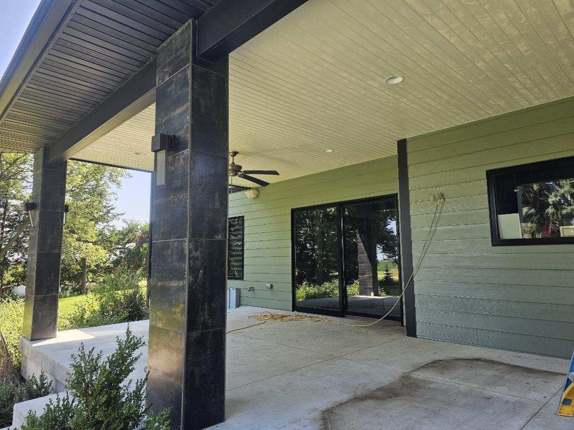 A newly painted porch with a ceiling fan and sliding glass doors on a house