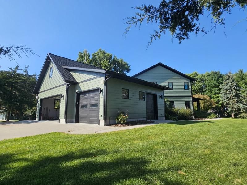 A newly painted house with a garage and a large lawn in front of it