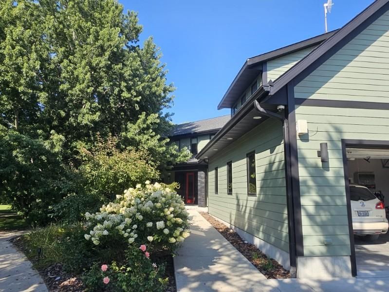 A green-painted house with a car parked inside the garage