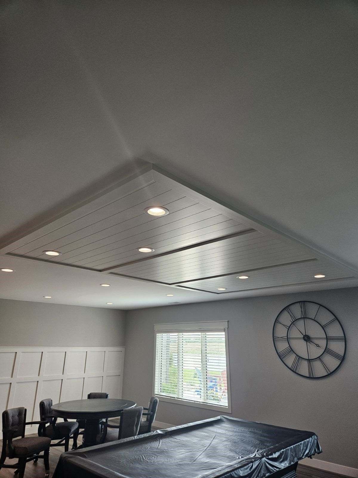 A game room with a pool table and a clock on the wall.